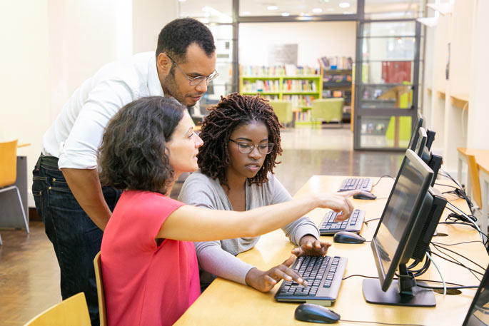 Instructor helping students in computer class Instructor helping students in computer class