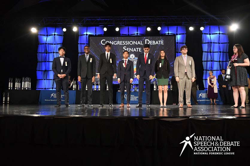 Group of students on the National Tournament stage with their trophies. Group of students on the National Tournament stage with their trophies.