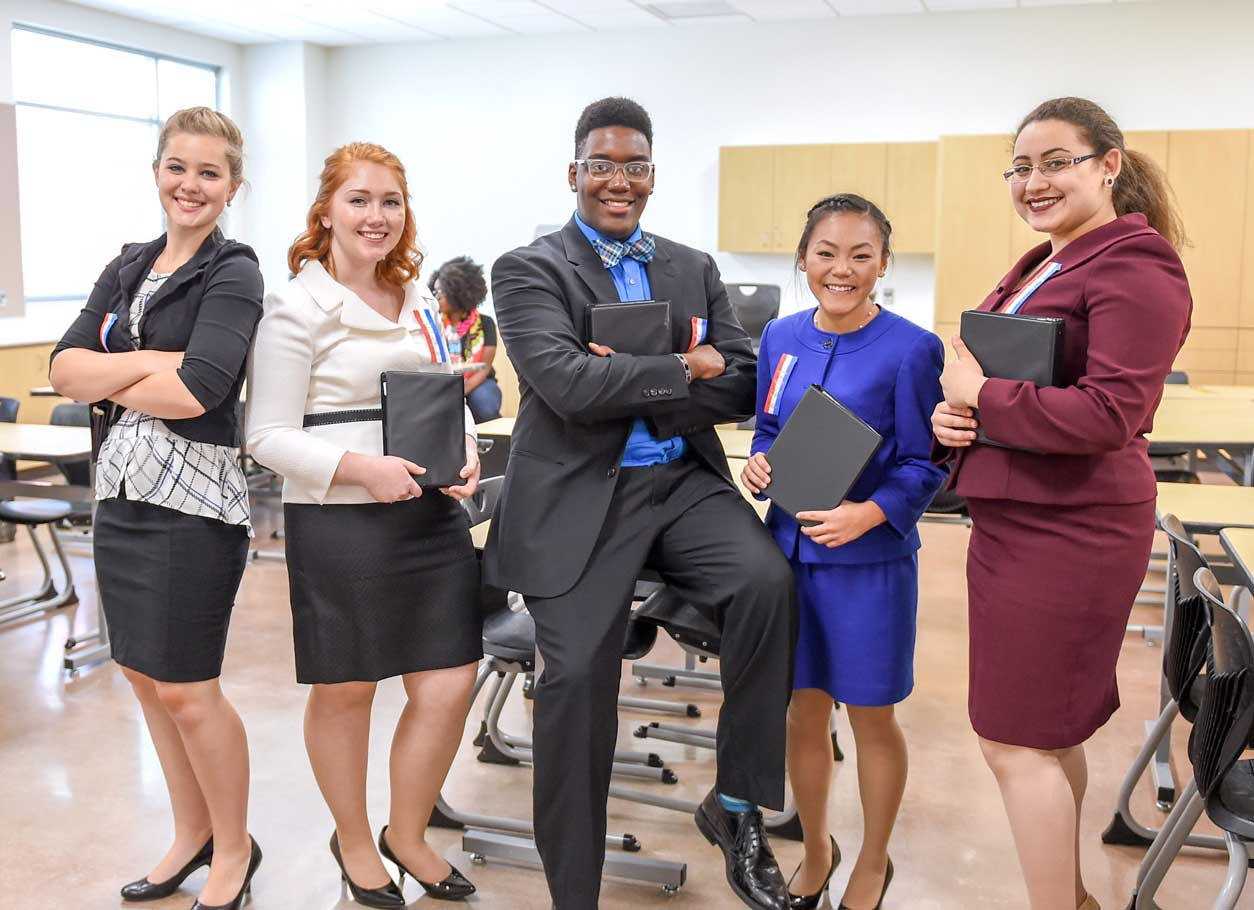 Group of students posing in a classroom with their binders