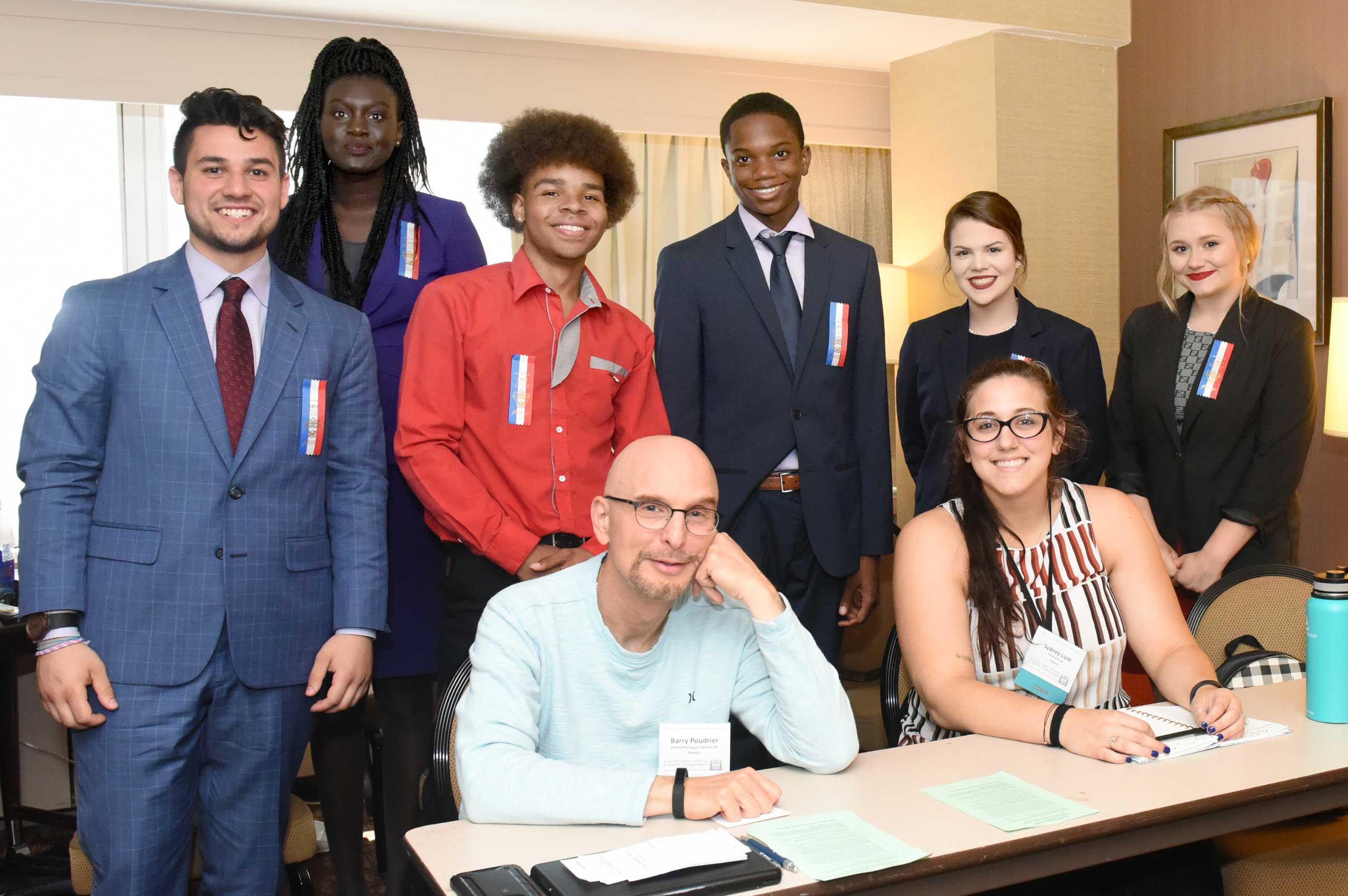Group of students and coaches in a room smiling