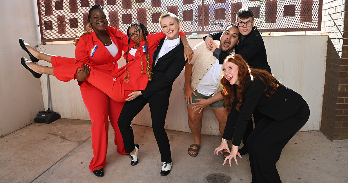 Students and their coach in a silly pose dressed in competition attire.