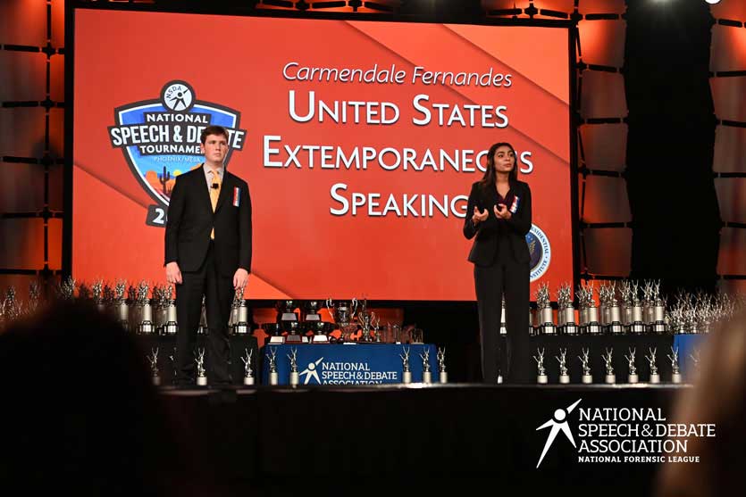 Group of students on the National Tournament stage with their trophies. Group of students on the National Tournament stage with their trophies.