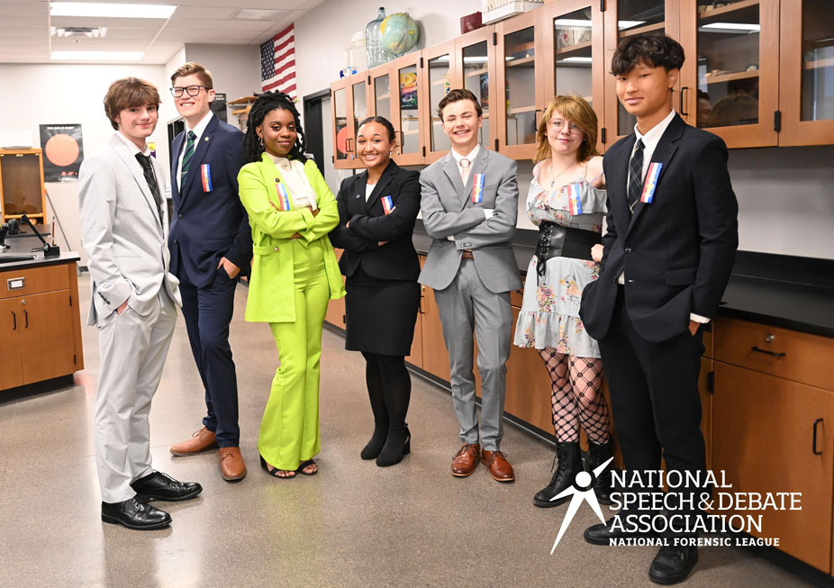 Group of students posing with their hands in the air smiling