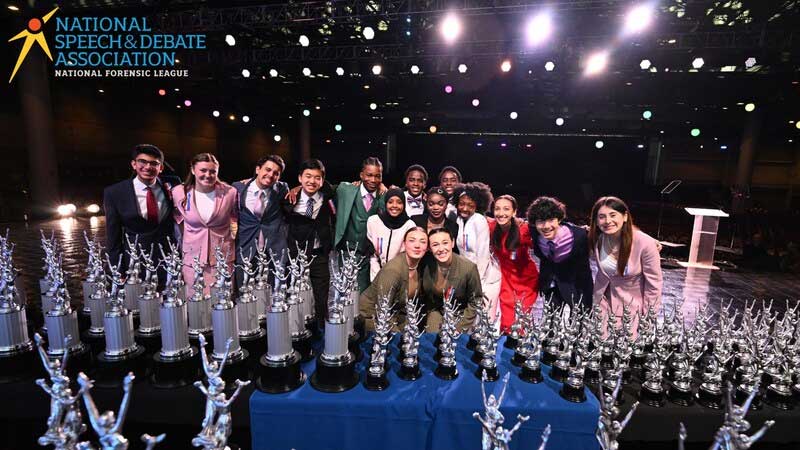 Students competing at the National Speech & Debate Tournament pose with trophies