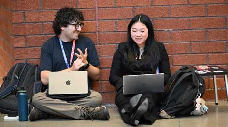 Intro to Coaching Speech and Debate Coach sitting with their student in a hallway