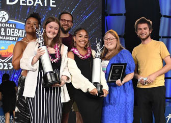 Group of students standing on stage at the National Tournament with their trophies