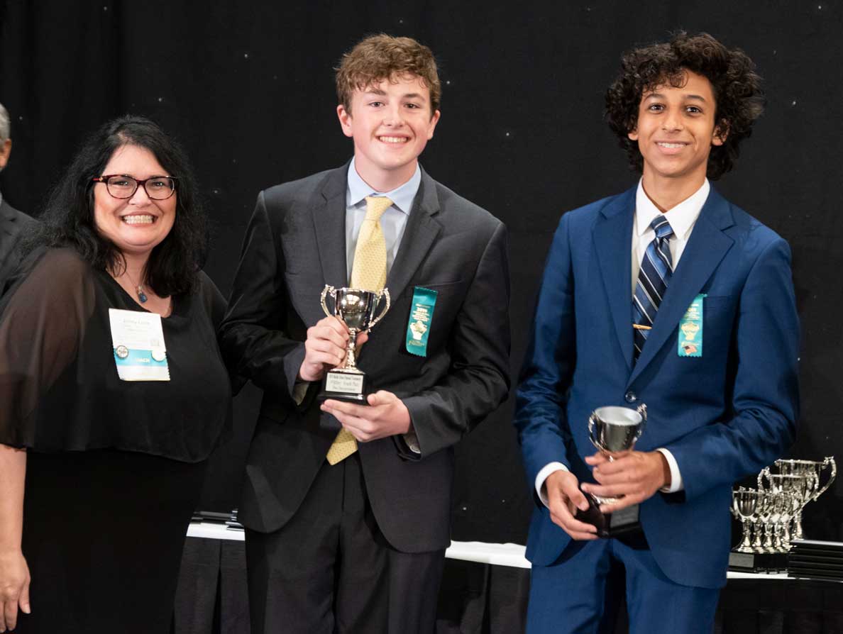 Coach posing with students and their awards during Nationals 