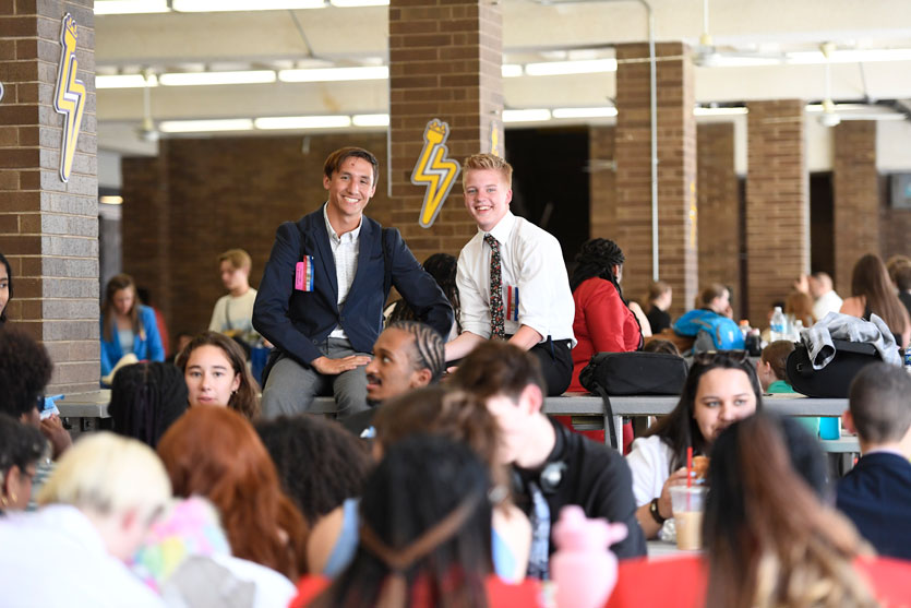 Two students in a crowded area sitting together