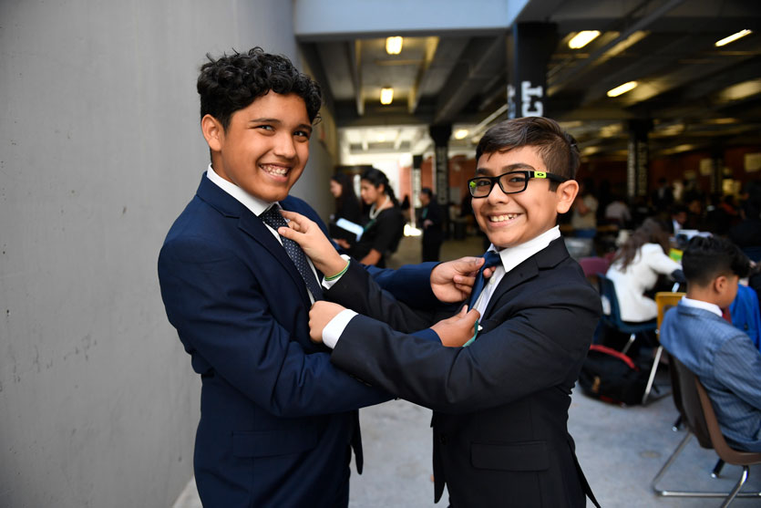 Two middle school students fixing their ties at a tournament