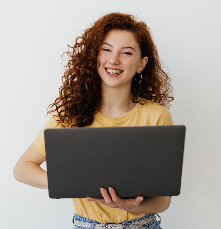 Person standing and smiling with a laptop Person standing and smiling with a laptop