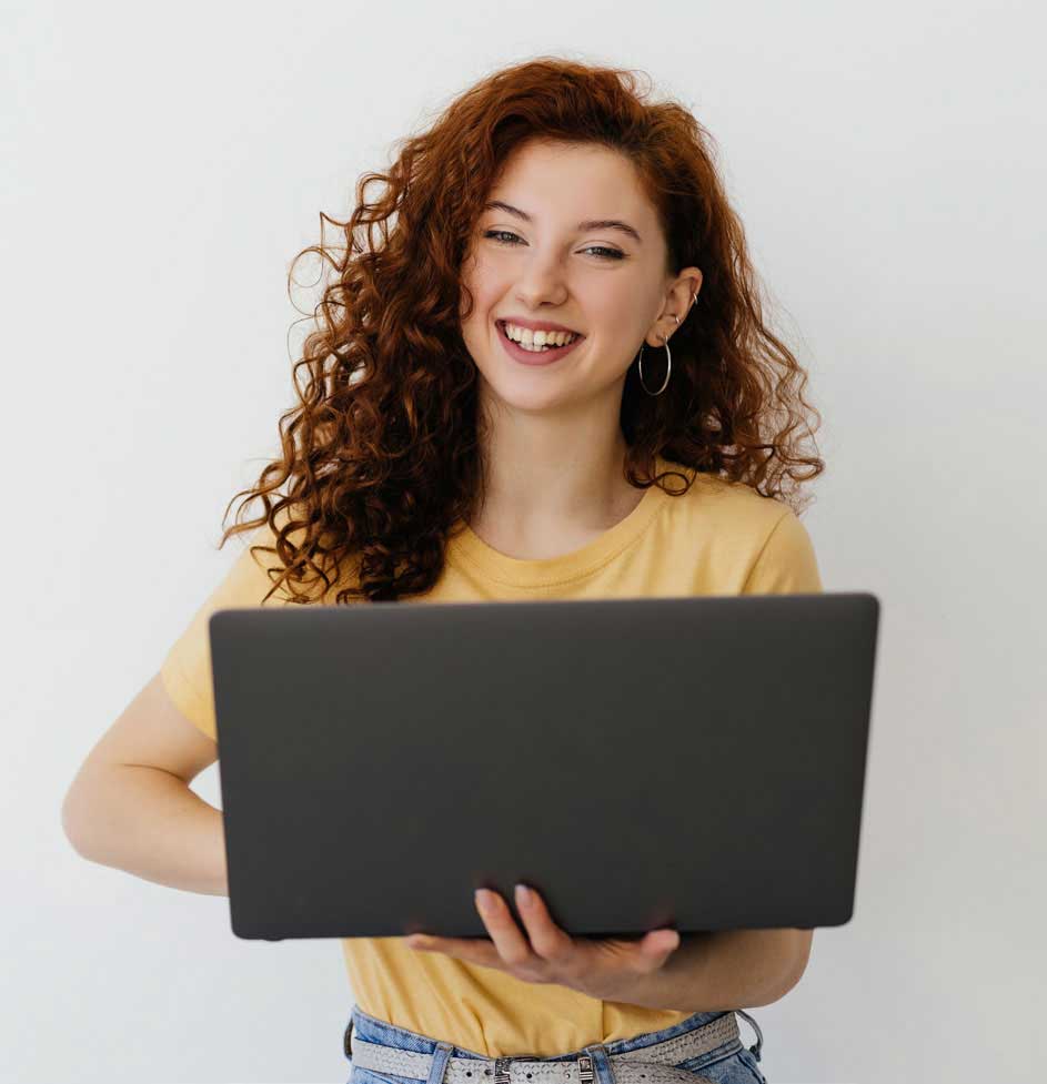 Person standing and smiling with a laptop Person standing and smiling with a laptop