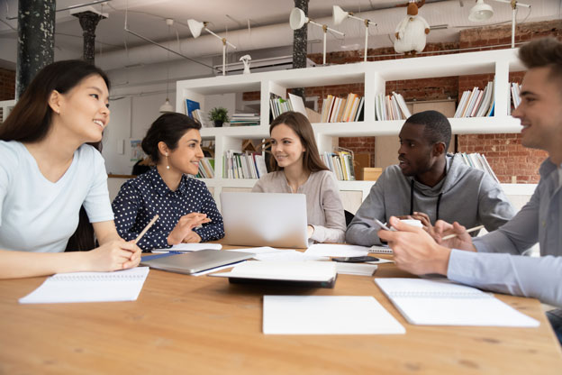 Group of people sitting together at table taking notes