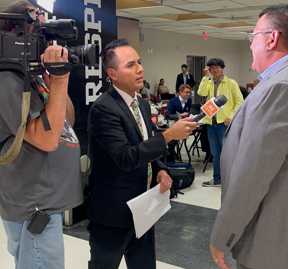 People speaking together in front of a media crew