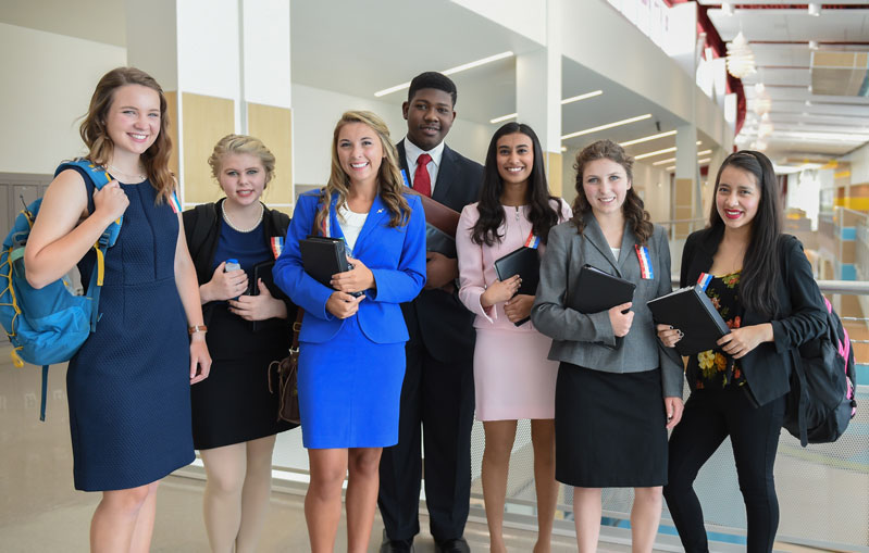 Group of students standing together in a hallway at a tournament smiling.