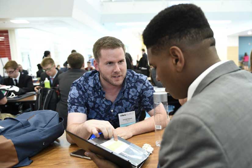 Coach speaking with a student at a table at the National Tournament