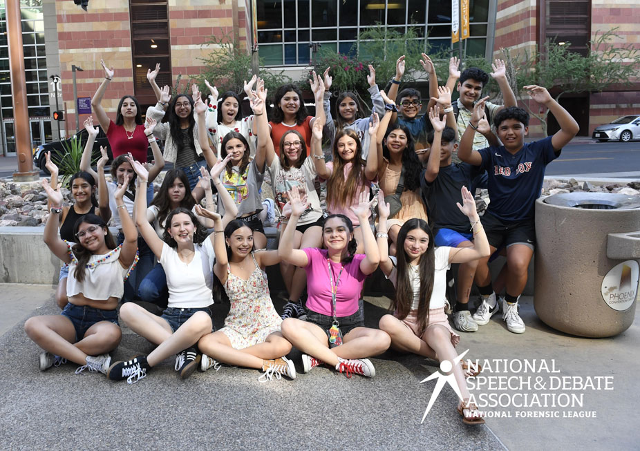 Group of students posing with their hands in the air smiling