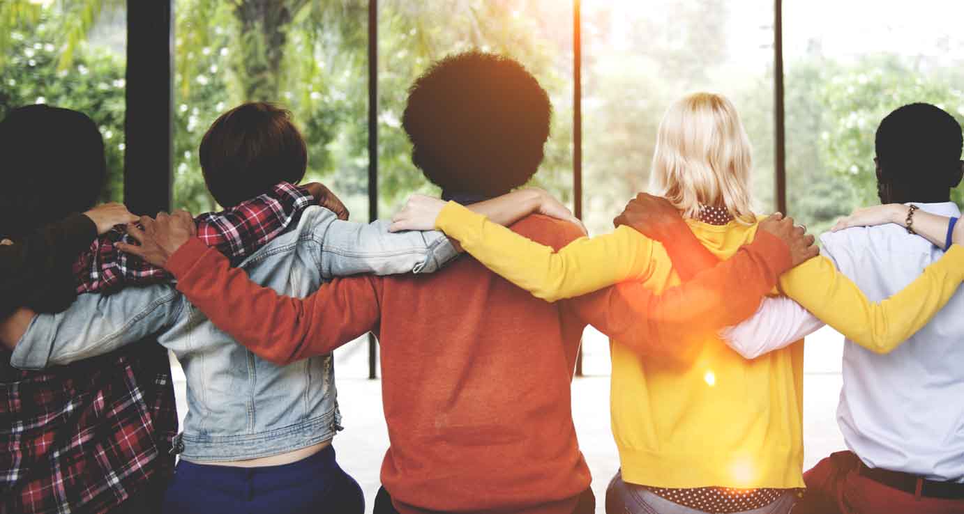 Group of people with their hands on their shoulders facing away 