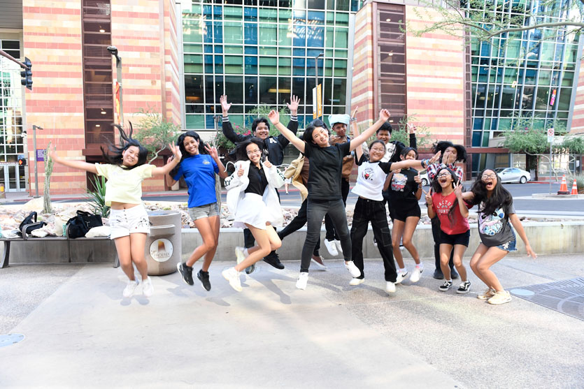 Group of students jumping in the air outside on a sidewalk